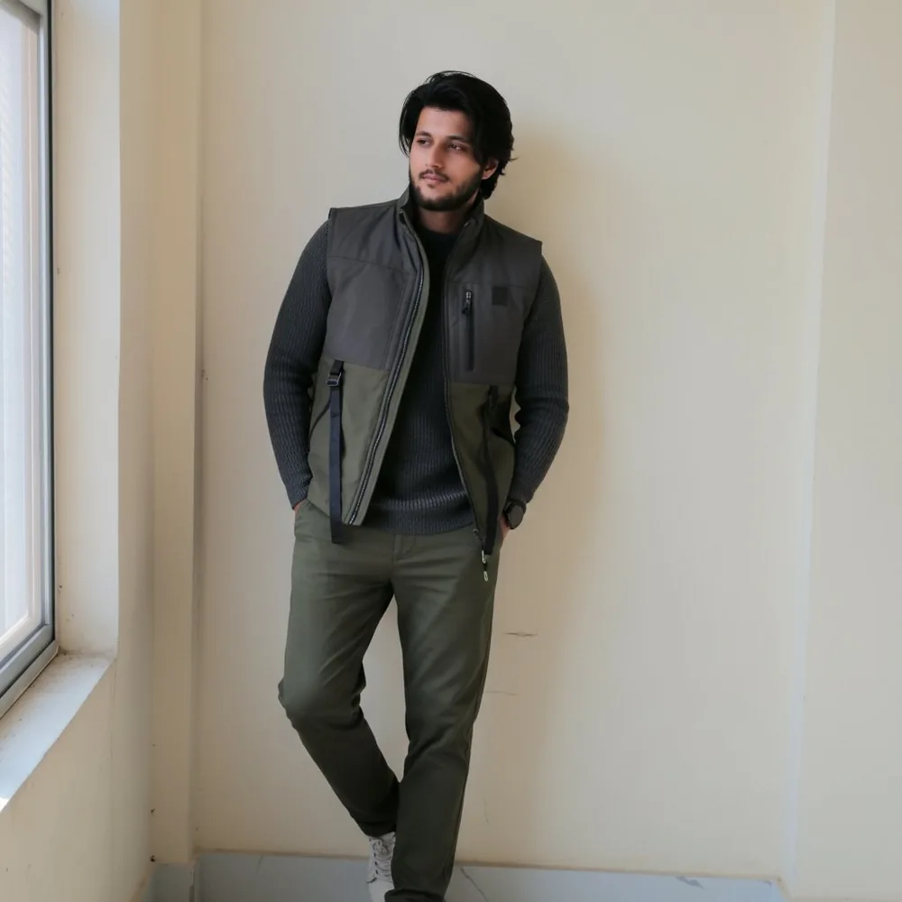 Khizer Javed portrait in a utility vest by a window